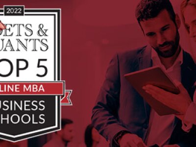 Next to the Poets & Quants logo, two people in business attire look at a tablet screen.