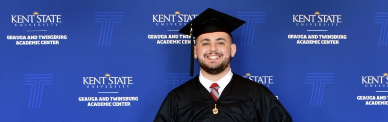 Kent State University graduate in cap and gown holding degree