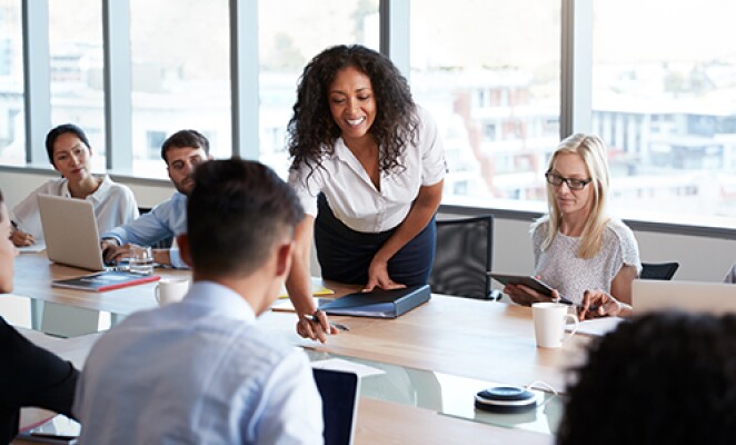woman assisting students sitting around a table