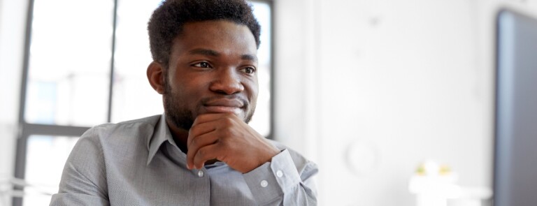 Young man sits in a room looking at a laptop