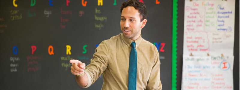 Male elementary school teacher standing in classroom