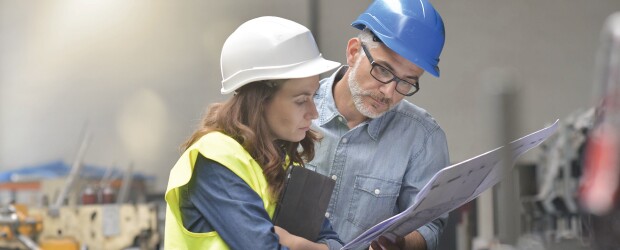 man and woman wearing hardhats looking at chart