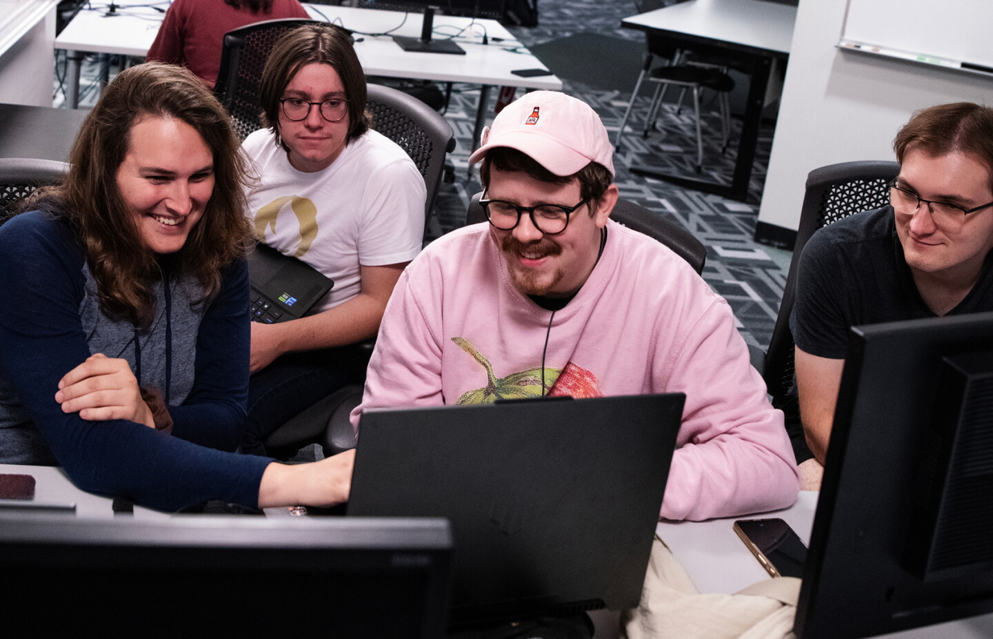 Group of students gathered around a computer workstation collaborating in a studio classroom.