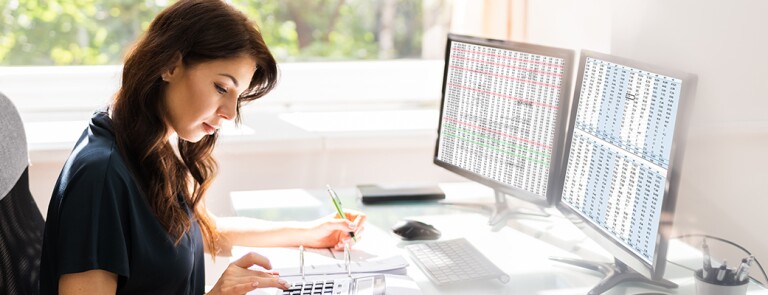 woman-using-calculator-and-computer-at-desk