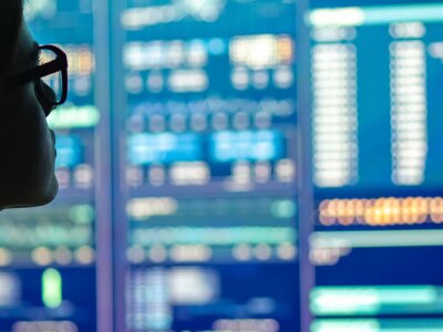 The businesswoman in glasses standing near monitor displaying business metrics and analytics.