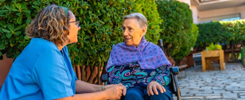 woman in wheelchair holding hands with nurse