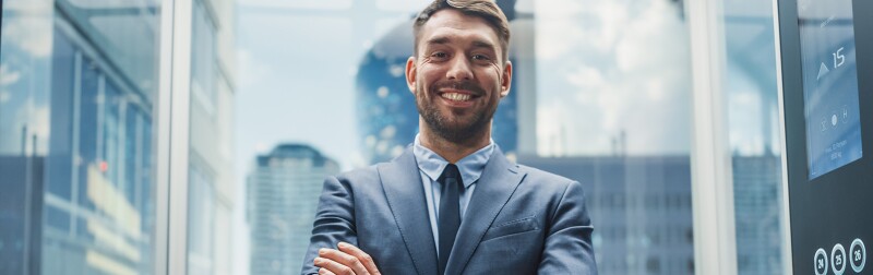 Successful businessman in the glass elevator of a modern office building