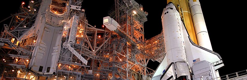 A Space Shuttle on the launch pad, against a dark sky