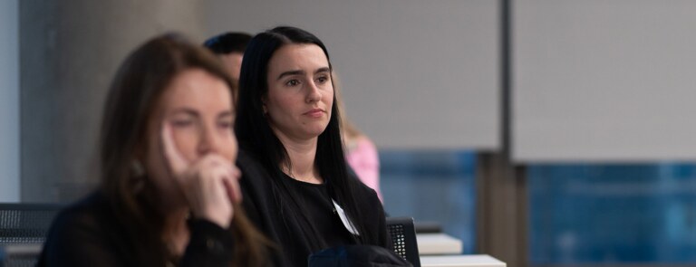 Two students listening to a speaker in a classroom