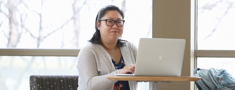 Confident student works on master’s in health care analytics on her laptop computer.