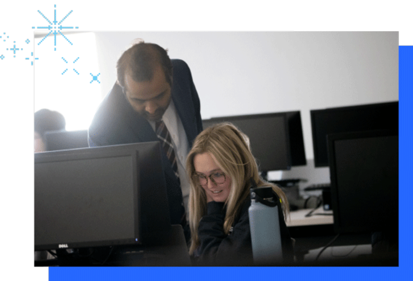 A male KU professor is leaning over a student working on a computer.