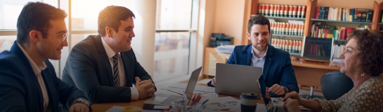 a group of professional conduct a meeting in a law office while working on laptops