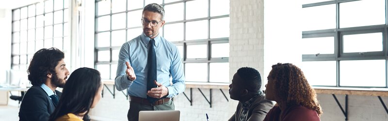 A business professional leading a discussion with a diverse group of colleagues in an MBA course environment.