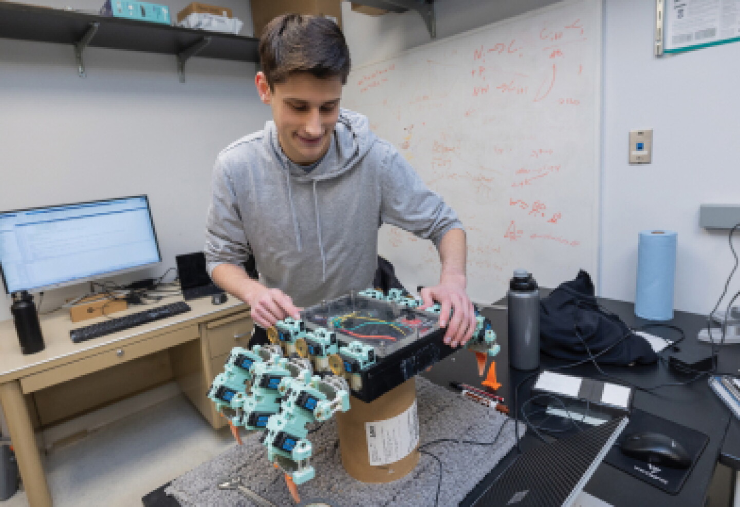 A male CWRU mechanical engineering student testing a mechanical device.