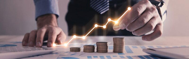 Man stacking coins with a graph of profit.