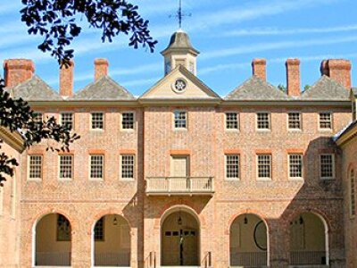 front-head-on-view-of-brick-building-with-blue-sky-and-streak-clouds-and-black-tree-branches-on-left