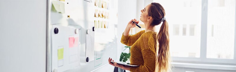 Instructional designer in office using whiteboard and tablet