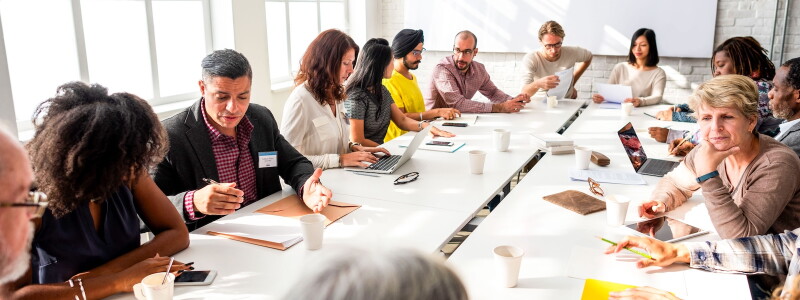 Diverse colleagues carry on collaborative discussion around a meeting table