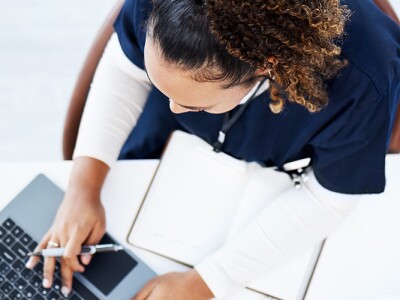 Overhead view of a nursing student studying at a desk with a laptop and books
