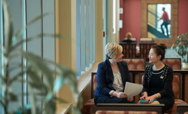 two women sitting on couch talking in business building
