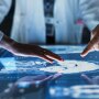 Doctors Interacting With Touch Screen On Table With MRI Scans Of Brain On Display.