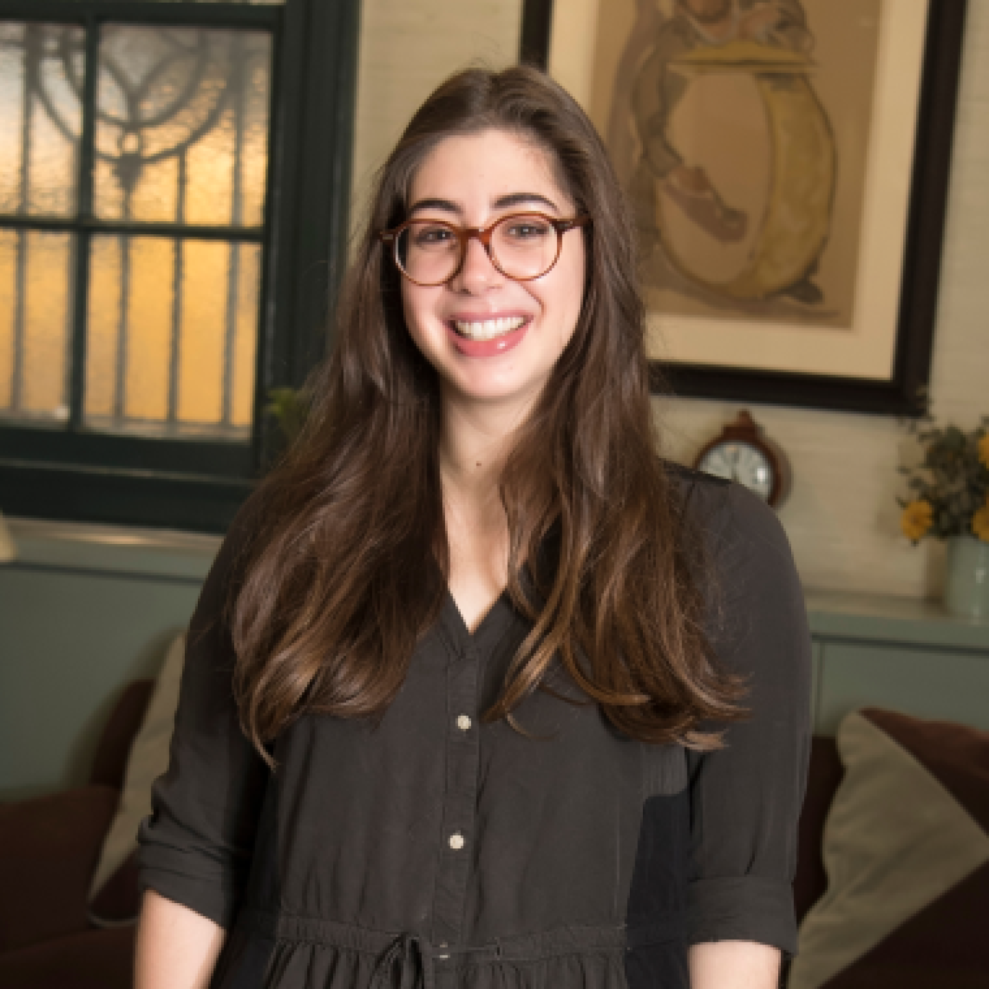 A female Yeshiva University student smiles while standing in a common area.