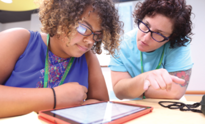 teacher with curly hair and glasses teaching female student