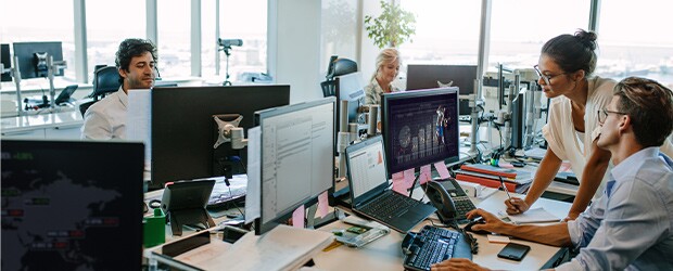 Office staff using computers to research top sports analytics jobs.