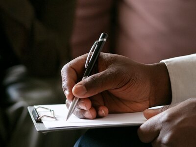 counselor wearing long sleeve white shirt taking notes on clipboard