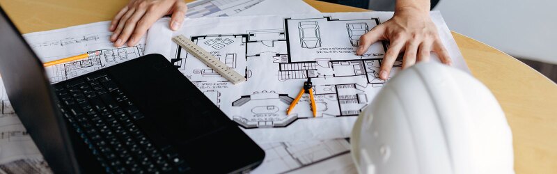 table filled with floor plans, laptop and other engineering things