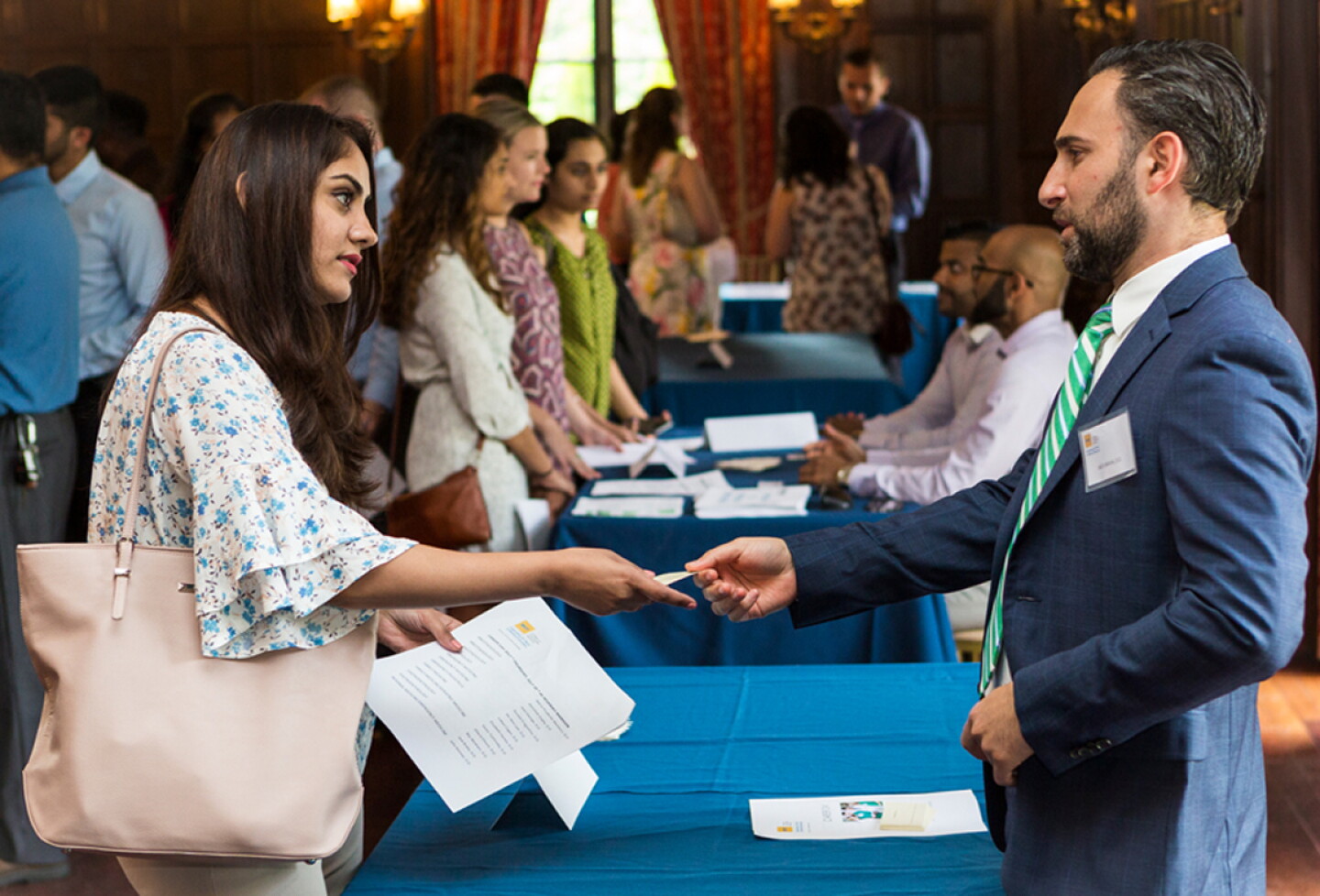 Student shaking a professional's hand over a table at a job fair.