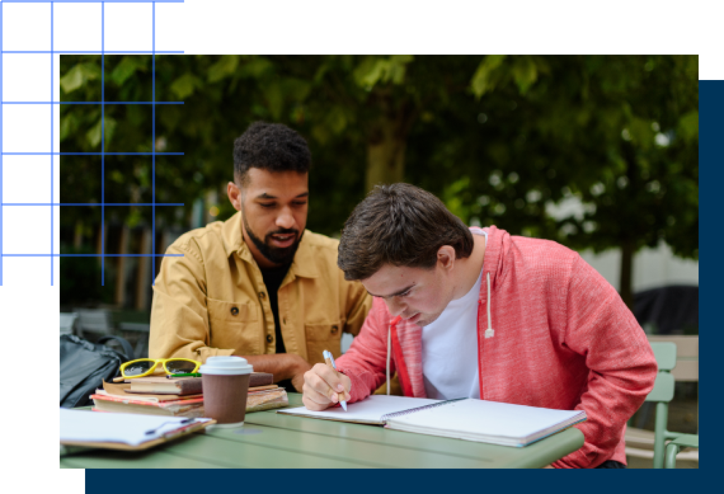 A male teacher assists a male student with a textbook lesson.