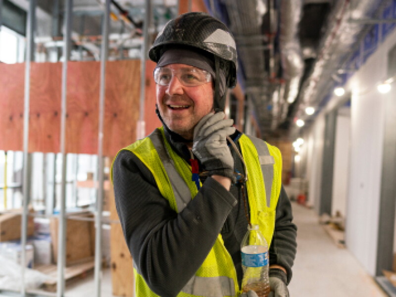 Close-up of a CWRU mechanical engineering student adjusting helmet strap on worksite.