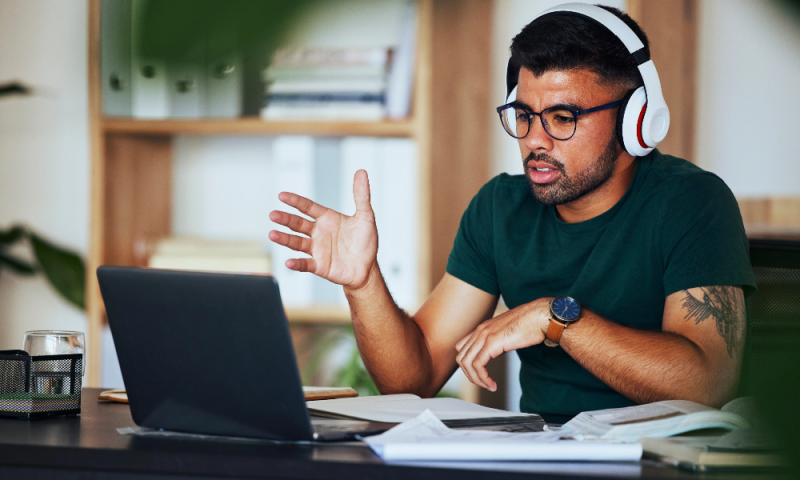 Male working on his laptop surrounded by books and notepads.
