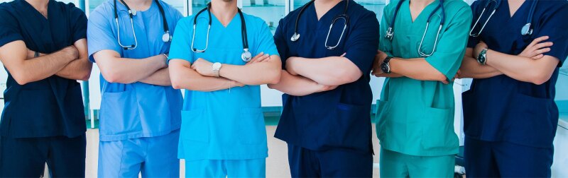 A group of faceless nurses stand together with arms crossed.