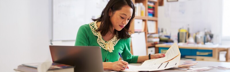 Female teacher at her desk working on student evaluations.