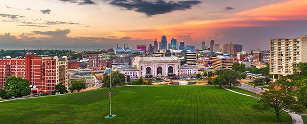 aerial-view-of-campus-city-in-background-at-sunset-green-lawn-in-front