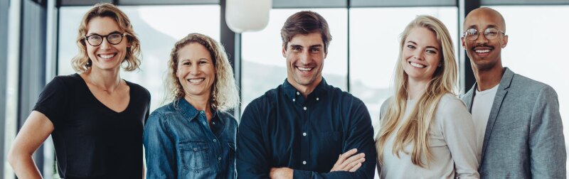 Successful business team standing together smiling, while in a conference room.