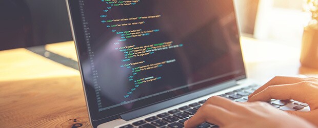 Closeup view of two hands typing code into a laptop