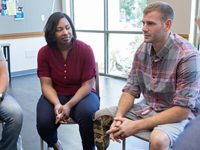 Group of adults sitting down looking at a man talking