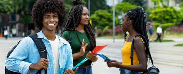 Man smiling with backpack and women talking outdoors