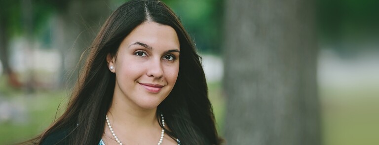 smiling woman with long black hair wearing pearl necklace with matching earrings
