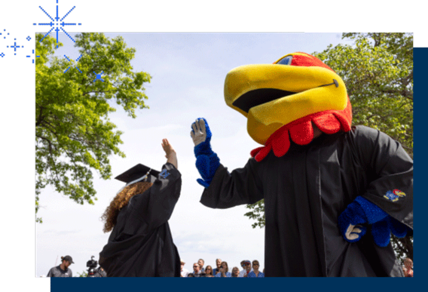 The KU Jayhawk mascot high-fives with a female KU graduate.