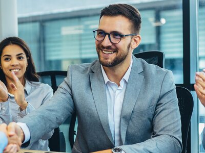Business professionals in a sports management setting celebrate a successful interview with a handshake and applause.