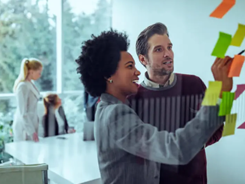 Marketing colleagues review notes on a transparent wall.