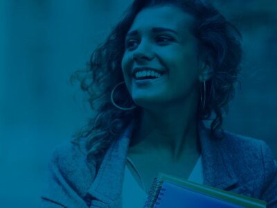 Young female business professional smiles while holding paper folders.