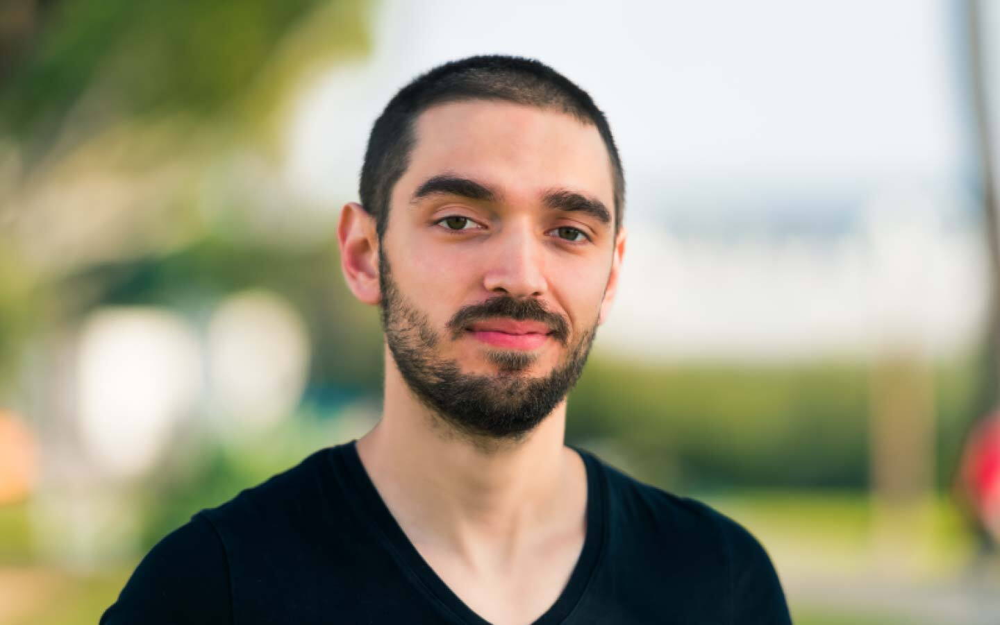 Bearded young man wearing black tees smiling for the camera.