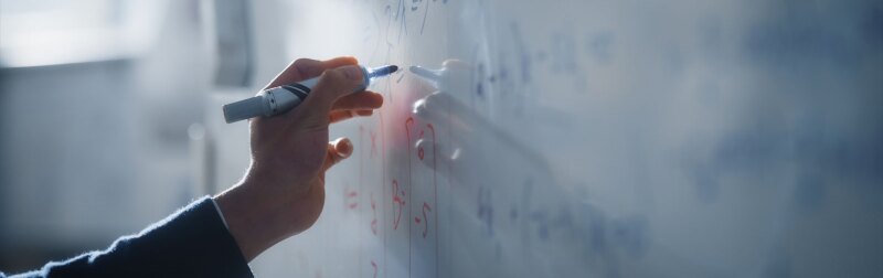 Teacher Writing Equations on a Whiteboard with Mathematical Formulas.