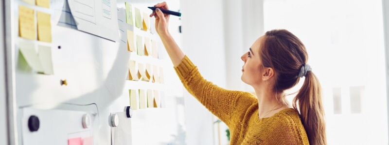 A woman creates a wire frame on a whiteboard for a learning design exercise
