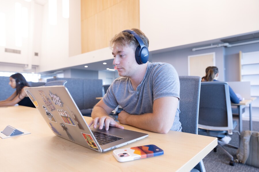 student wearing headphones while using a laptop